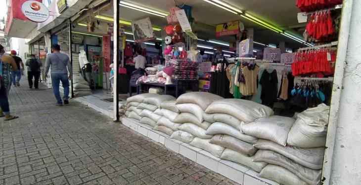 Por precaución, comercios dejan costalería en sus entradas